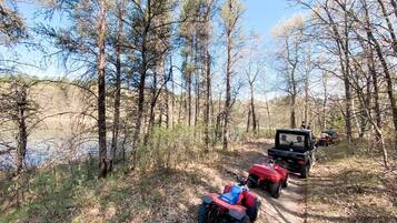 A forested area with a dirt path and ATVs.
