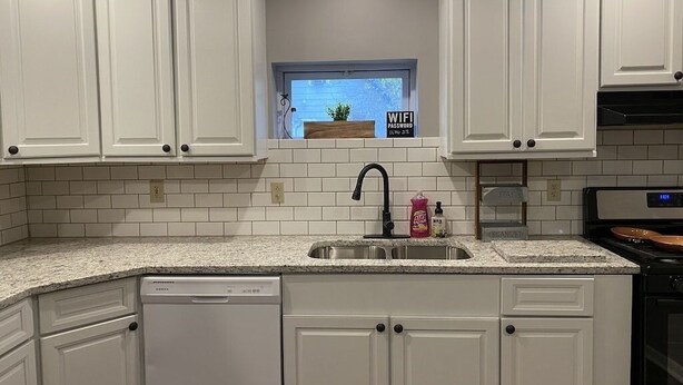 A kitchen with white cabinets, a granite countertop, a built-in dishwasher, a window with a view, and a sign indicating a WiFi password. - **Stylish Pet Friendly 3 Bedroom House** (Cleveland)