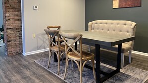 A dining area with a table and two chairs, a brick wall, and a painting on the wall. - **Stylish Pet Friendly 3 Bedroom House** (Cleveland)