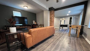 A modern living room with a sofa, a TV, and a pool table. - **Stylish Pet Friendly 3 Bedroom House** (Cleveland)