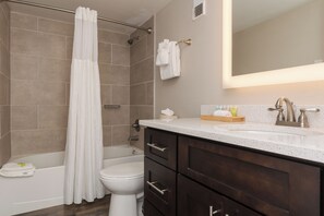 Et badeværelse med badekar, toilet og et vaskeskab med spejl.