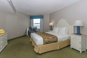 Une chambre d’hôtel avec un lit, des tables de chevet, une commode et une vue sur l’océan.