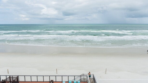 A beach with a view of the ocean, a staircase leading down to the beach, and a railing along the edge.