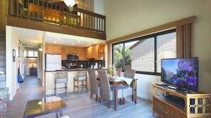 Relax in a spacious living area with a balcony overlooking a lush garden, perfect for unwinding and enjoying the view.