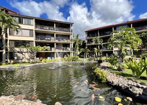Relax in a serene courtyard with a tranquil pond and koi fish, surrounded by lush landscaping and comfortable outdoor seating.