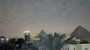 A view of the pyramids at night with buildings in the foreground. - Sphinx Safari (Giza)