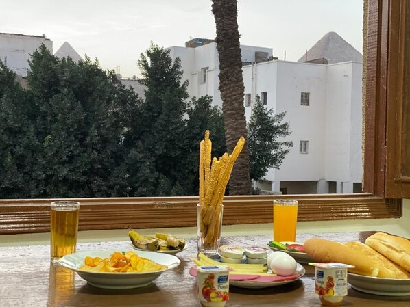 Una mesa con comida y bebidas, vista de edificios y una palmera.