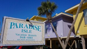 A sign for Paradise Isle Vacation Rentals with contact information and address.