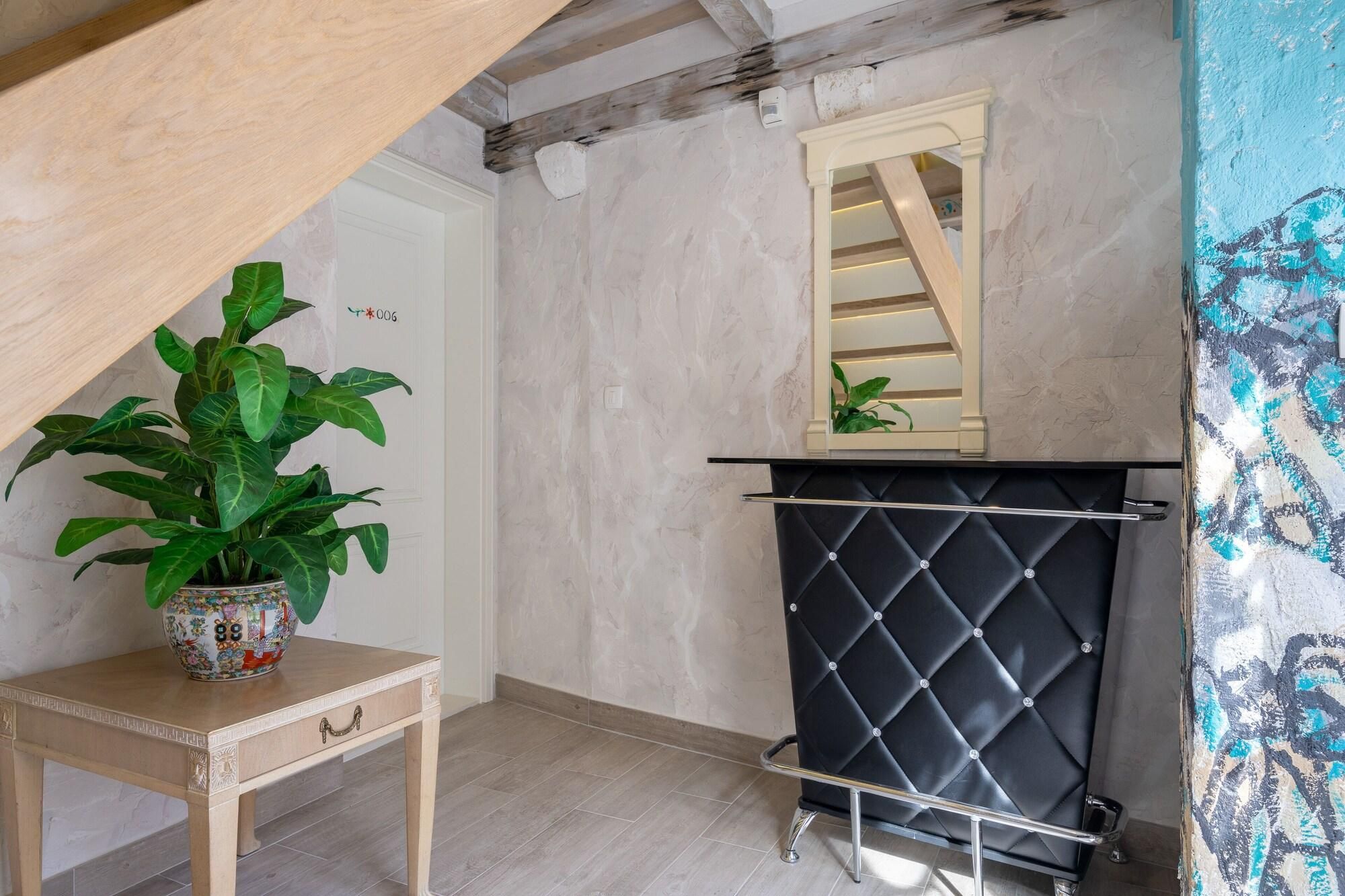 A room with a wooden table, a potted plant, a black cushioned bench, and a mirror on the wall.