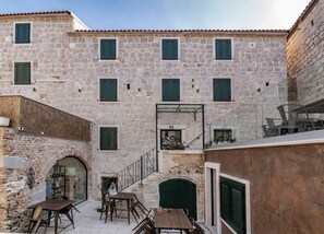 Un bâtiment en pierre doté de nombreuses fenêtres et d’un escalier menant à un étage supérieur.