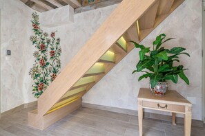 Una escalera con escalones de madera y un adorno floral en la pared.