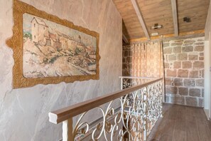 A rustic interior with a stone wall, a wooden ceiling, and a metal railing.