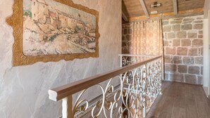 Ein rustikales Interieur mit einer Steinwand, Holzbalkendecke und einem Metallgeländer.