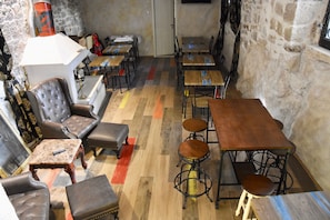 A cozy restaurant with wooden tables and leather chairs, stone walls, and a patterned floor. - Historic Plaza Varos Split (Split)