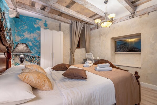 A hotel room with a bed, a nightstand, a lamp, a painting, and a wooden ceiling.