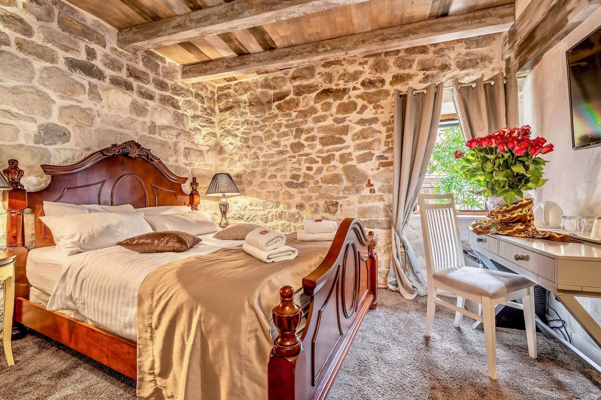 Une chambre aux murs de pierre, avec un lit en bois, un bureau et une chaise.
