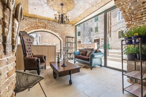 Una habitación acogedora con pared de ladrillo, un candelabro, un sillón de cuero, un sofá azul y una mesa de centro.