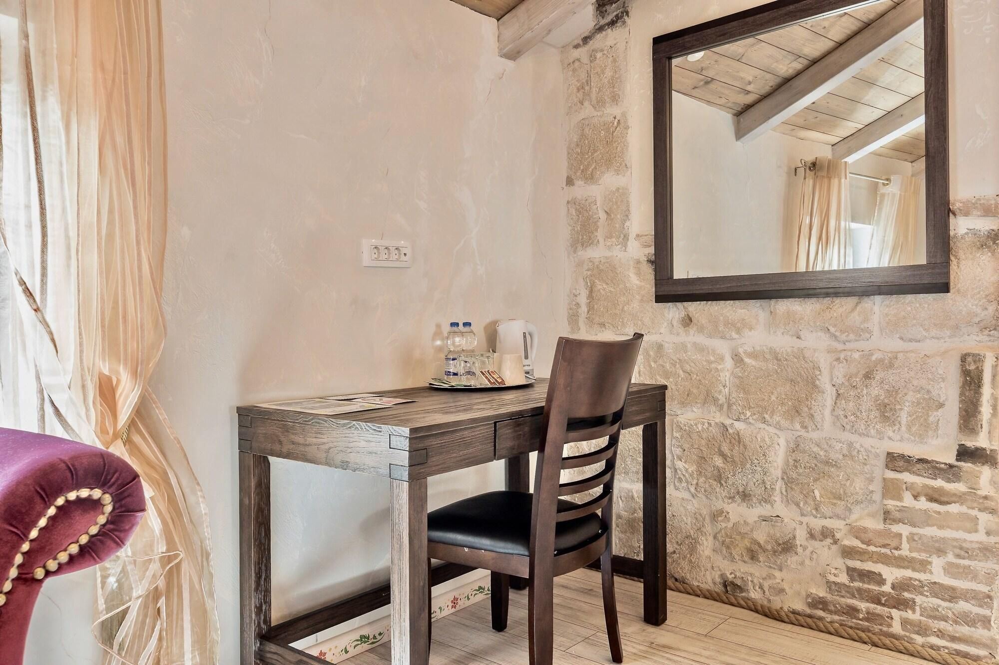 Une pièce rustique avec une table en bois, une chaise, un miroir et un mur en pierre.