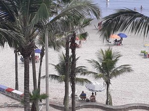 A beach with palm trees, umbrellas, and people relaxing.