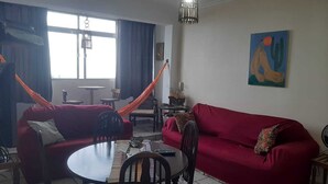 Un salon avec un canapé rouge, une table ronde et un hamac.