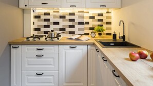 A compact kitchen with white cabinets, a black and white checkered floor, a wooden countertop, and a black faucet. - Beautiful house in Lee's Summit (Lee's Summit)