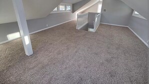 An attic bedroom with a sloped ceiling, a carpeted floor, a white railing staircase, and a skylight. - Beautiful house in Lee's Summit (Lee's Summit)