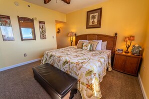 A bedroom with a large bed, a bench, a nightstand, and wall art.