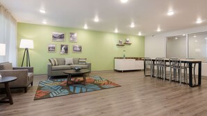 Ein Wohnzimmer mit Sofa, Couchtisch und Sesseln, ein Essbereich mit Tisch und Stühlen sowie eine Küche mit Schränken und Arbeitsplatte.