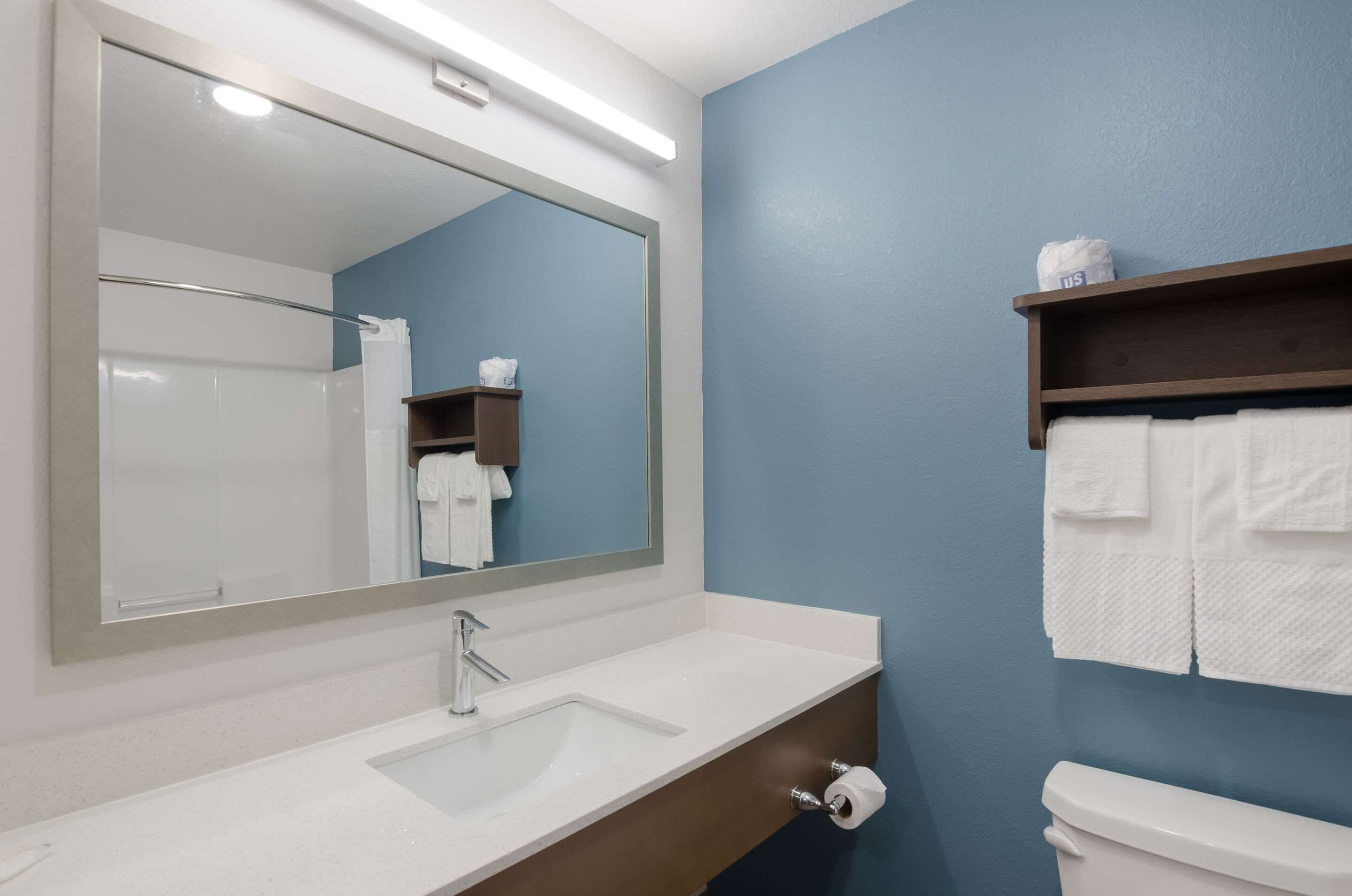 Une salle de bain avec un lavabo blanc, un miroir, des toilettes et un porte-serviettes.