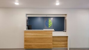 Ein Empfangsschalter mit blauer Wand und einem Logo, eine Holztresen und ein weißer Schreibtisch.