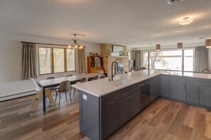 Een moderne keuken met een groot eiland, donkere kastjes en een stenen openhaard.