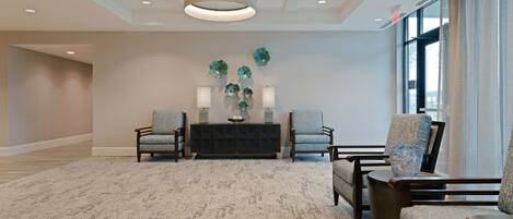 A spacious lobby with a patterned carpet, a dark console table with decorative items, and two upholstered armchairs.