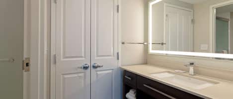 A modern bathroom with a double door, a large mirror, a sink, and a towel rack.