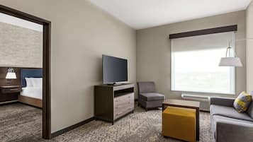A hotel room with a bed, a TV, a sofa, a chair, and a window with a view.
