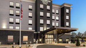 Um hotel moderno com fachada escura, várias janelas e uma bandeira americana.