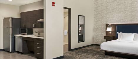 A hotel room with a bed, a bathroom, and a kitchenette.