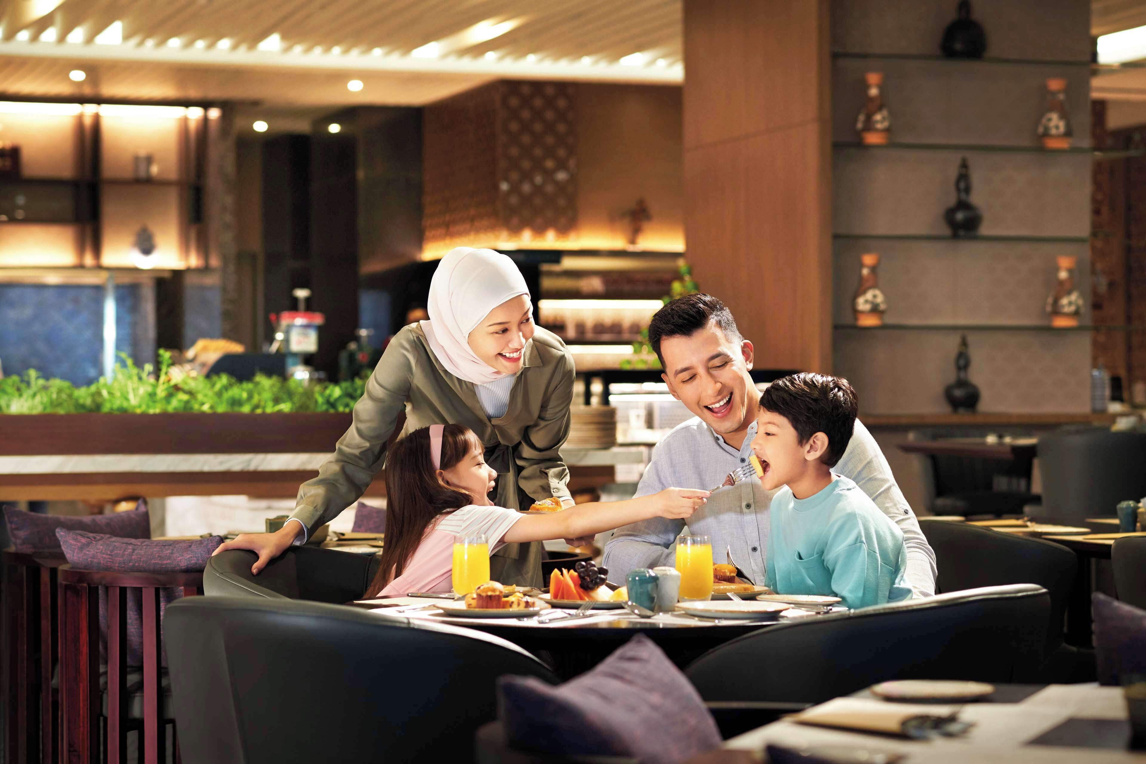 A family dining at a restaurant with a modern interior, including a bar area and decorative shelves.