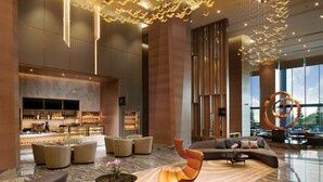 A spacious lobby with a bar area, seating arrangements, and a large window offering a view.