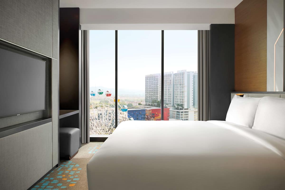 Una habitación de hotel moderna con una cama grande, televisión y vista a la ciudad.