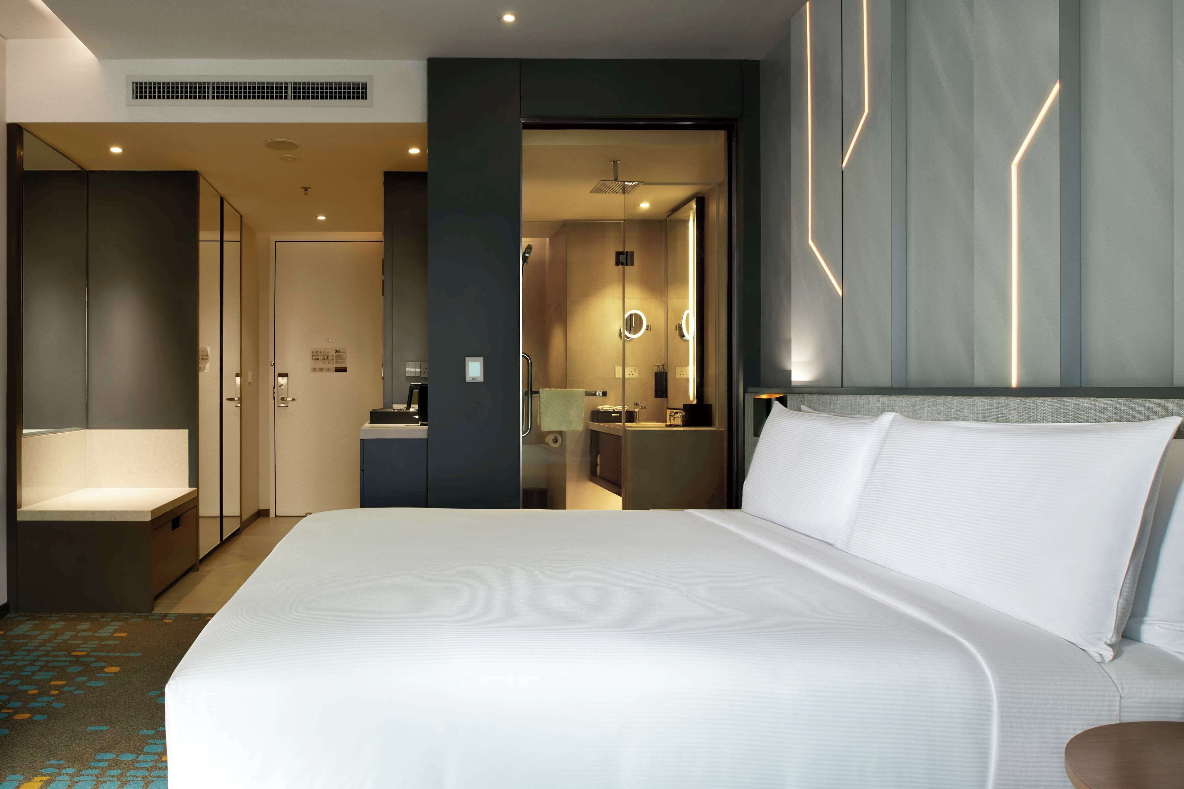 Une chambre d’hôtel moderne dotée d’un grand lit, d’une salle de bain séparée et d’un petit coin salon.