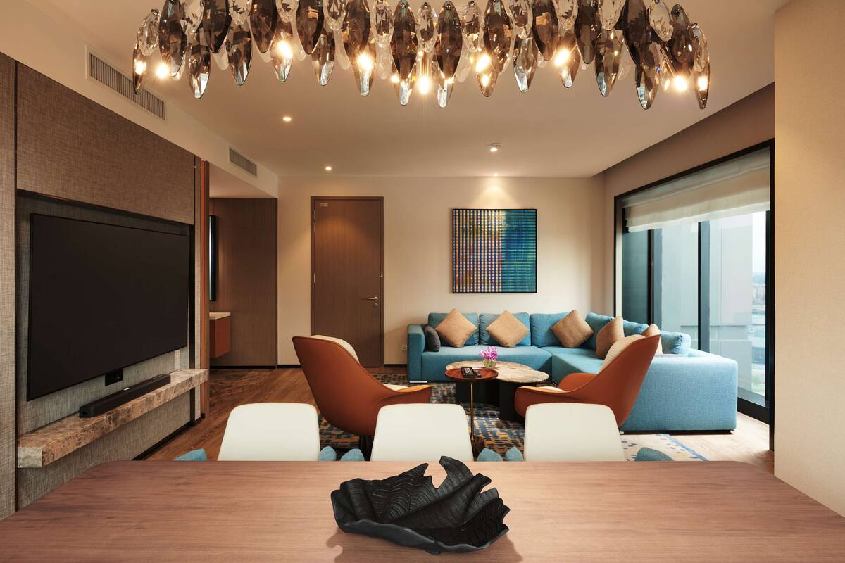 Una sala de estar moderna con un televisor de pantalla plana grande, una mesa de centro de madera y un sofá azul con cojines.