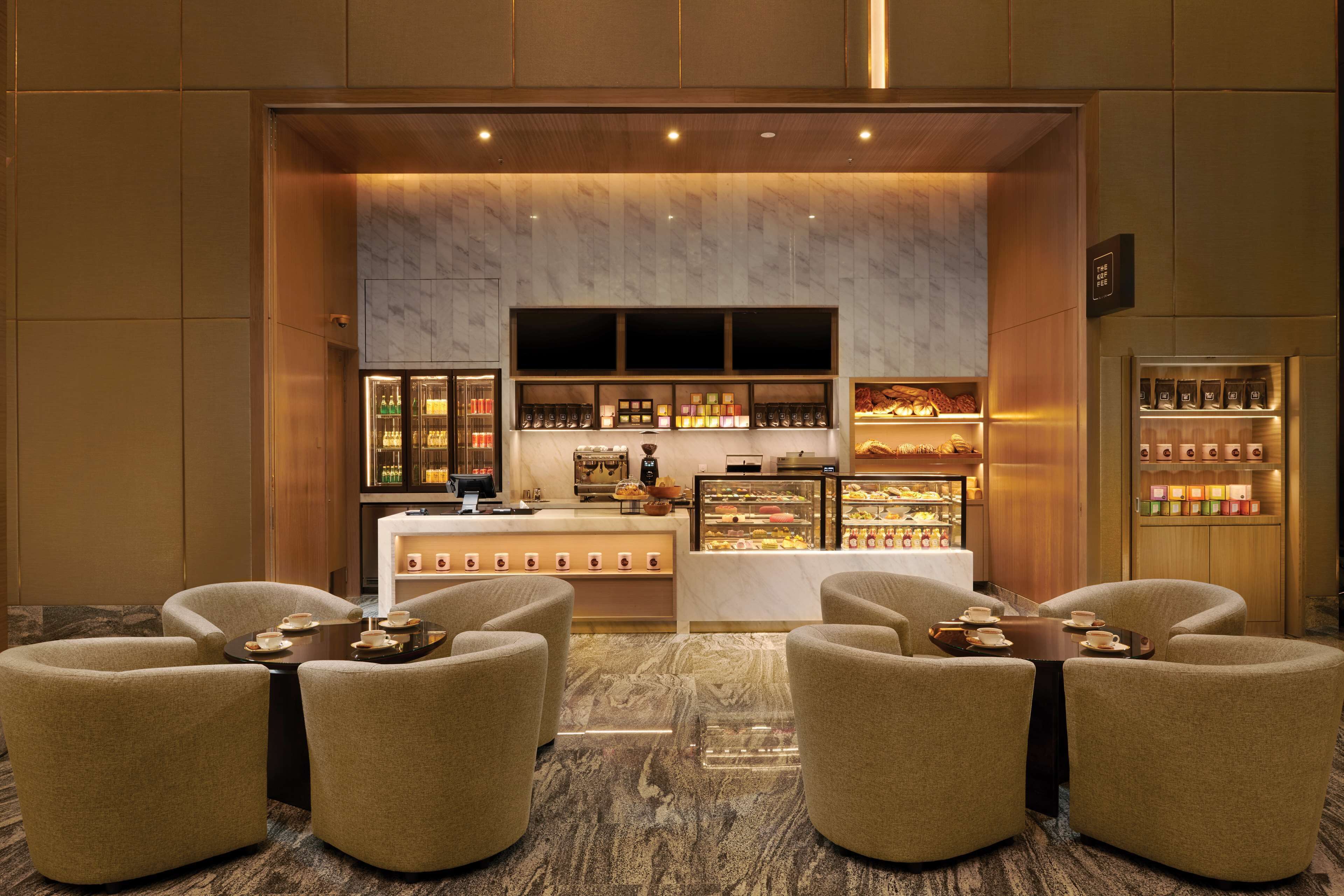 A hotel lobby with a coffee bar, seating area, and display cases.