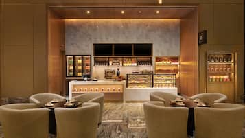 A hotel lobby with a coffee bar, seating area, and display cases.