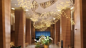 A spacious lobby with a high ceiling and a central floral arrangement.