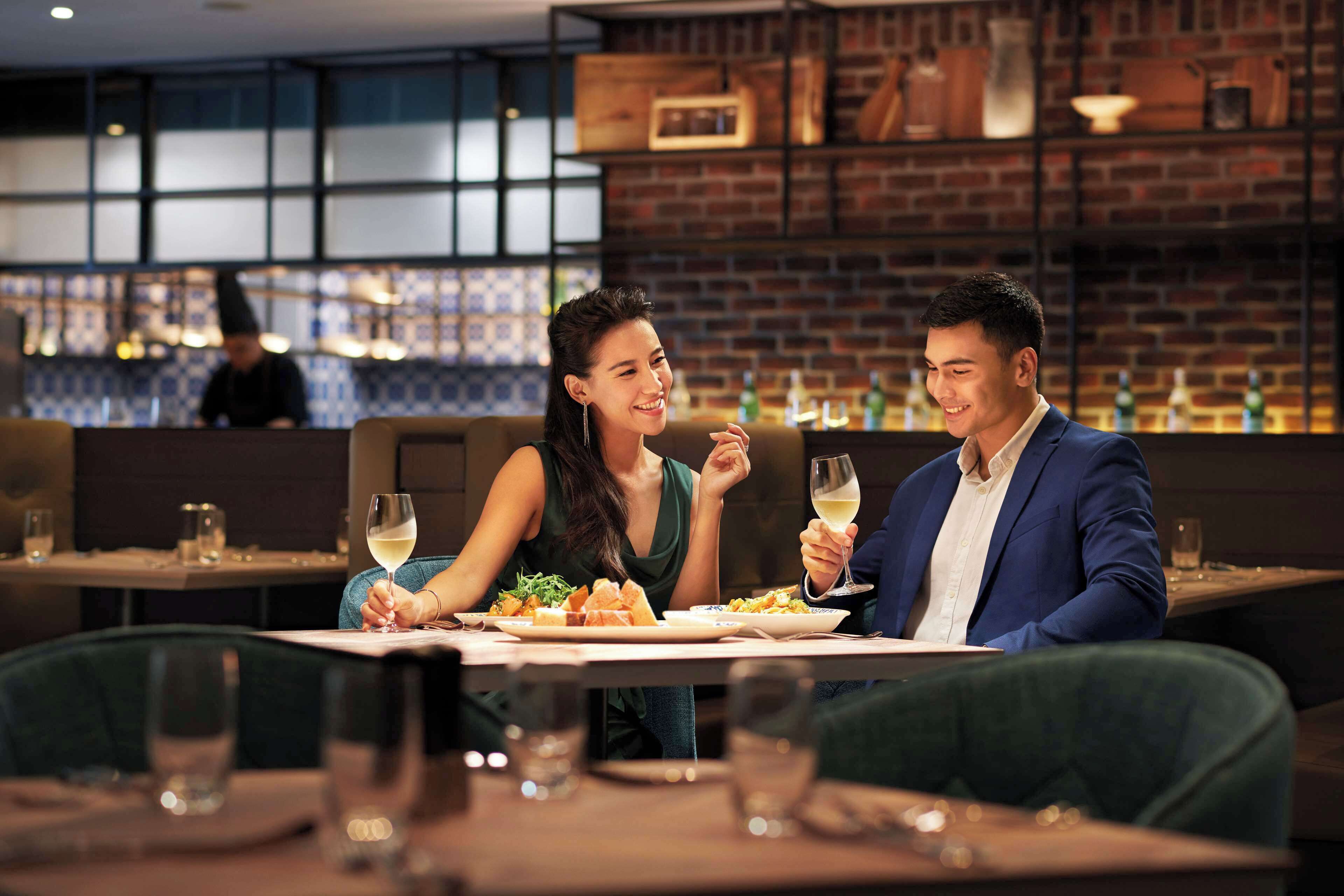 A couple dining at a restaurant with brick walls and a bar in the background.