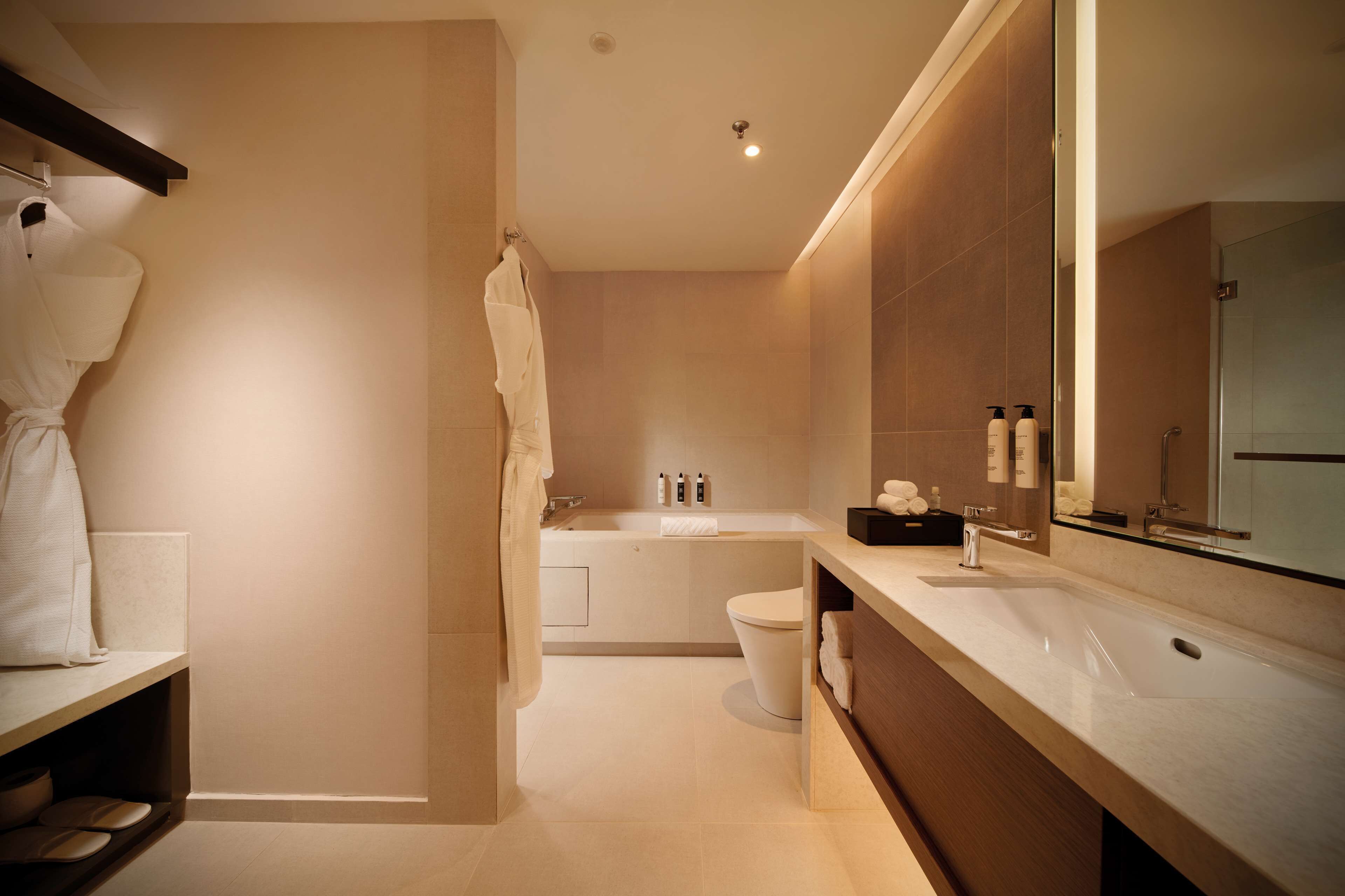 Een moderne badkamer met een bad, toilet en wastafel.