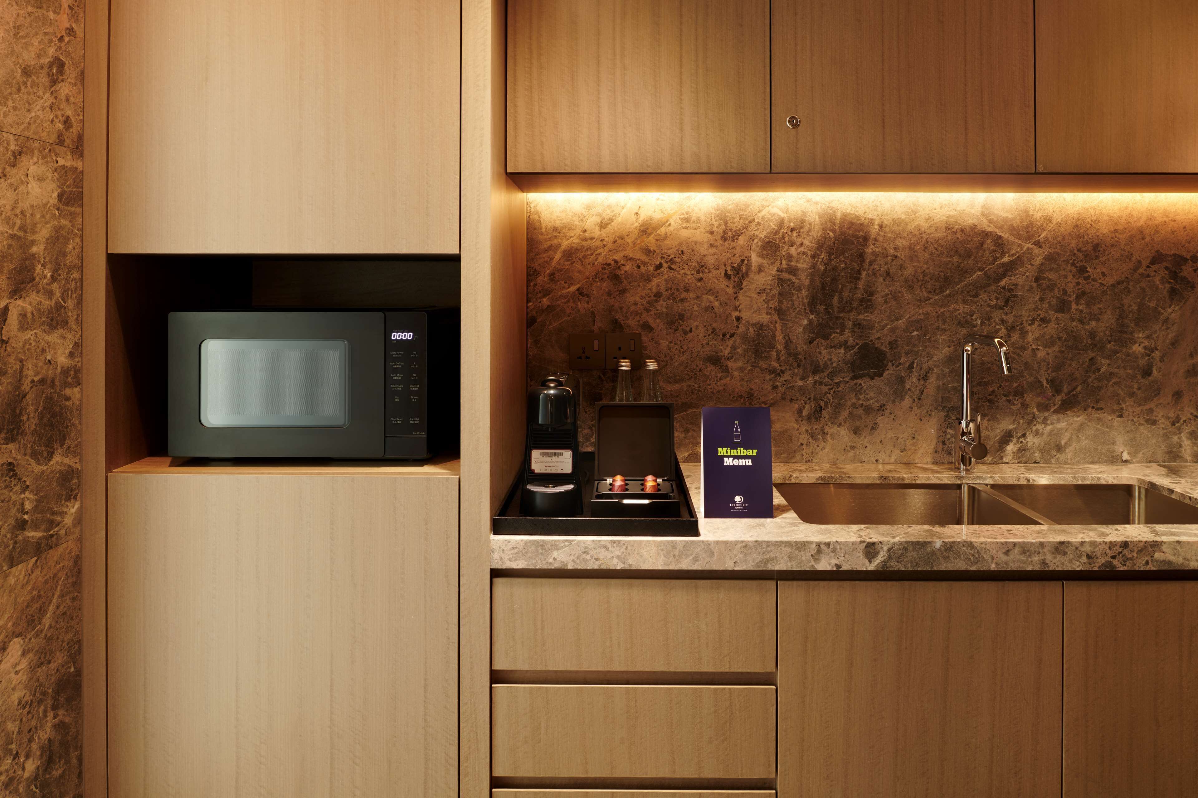 Una cocina moderna con microondas integrado, una cafetera y una botella de vino en la encimera.