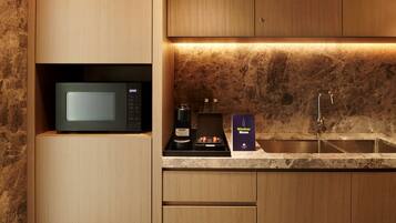 Una cocina moderna con microondas integrado, una cafetera y una botella de vino en la encimera.