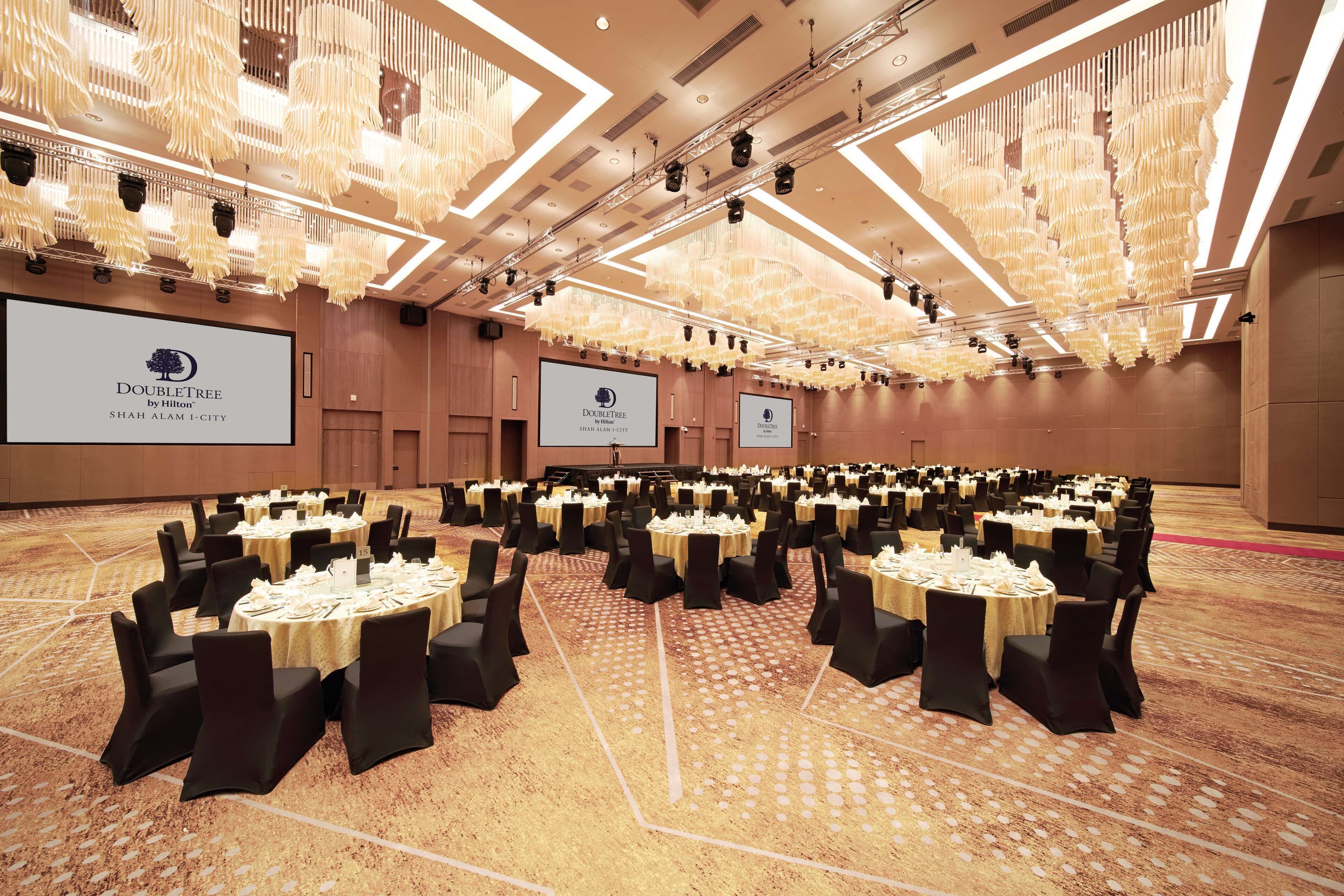 A large conference room with multiple round tables, black chairs, and a carpeted floor.
