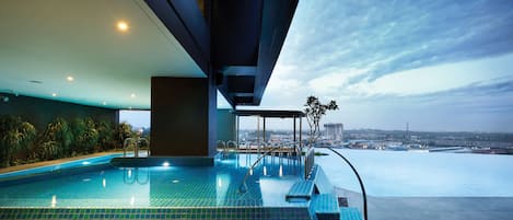 Una piscina al aire libre, sombrillas, sillones reclinables de piscina